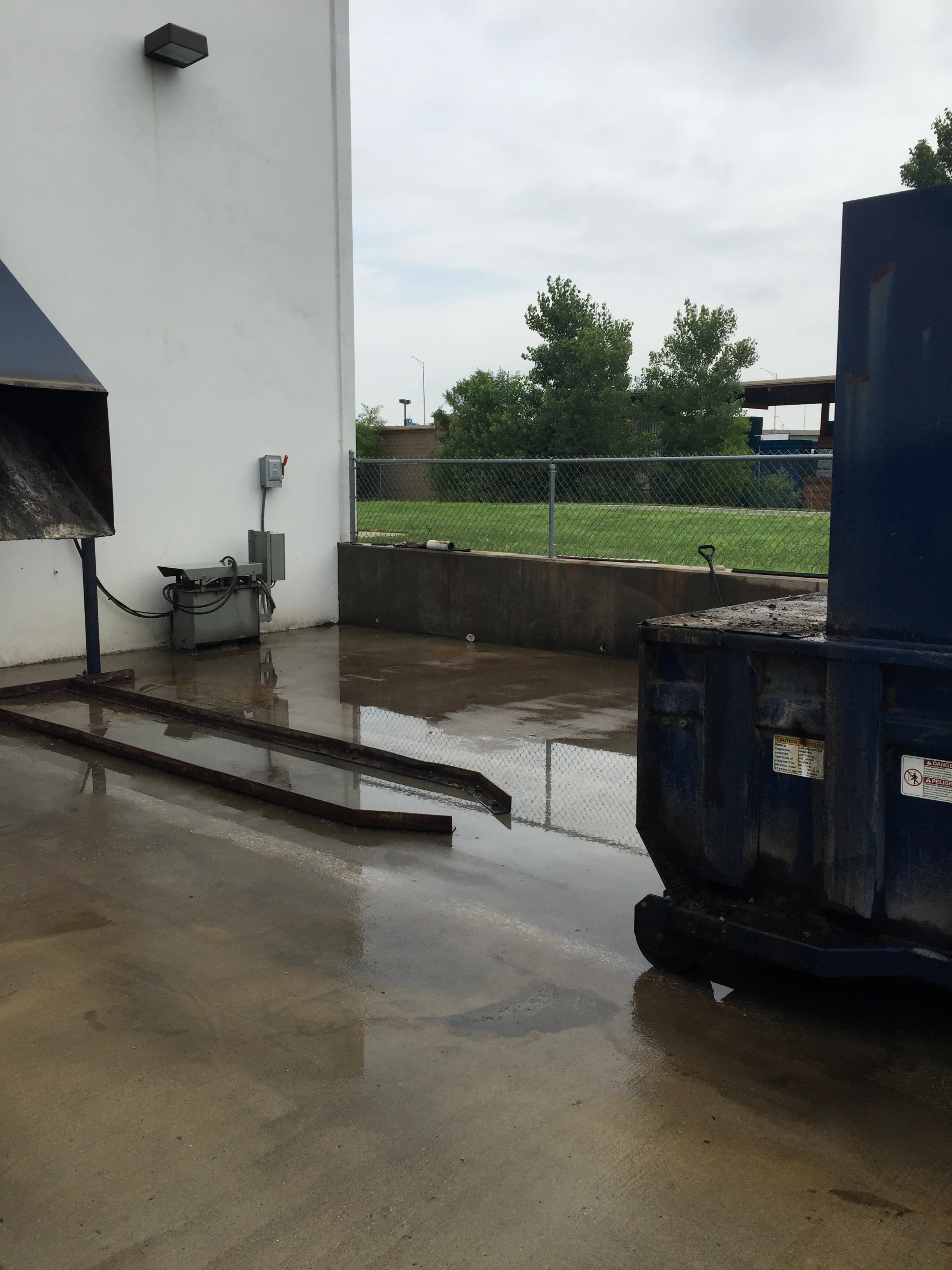 Pressure-washed concrete pad with metal basin and industrial equipment at commercial facility