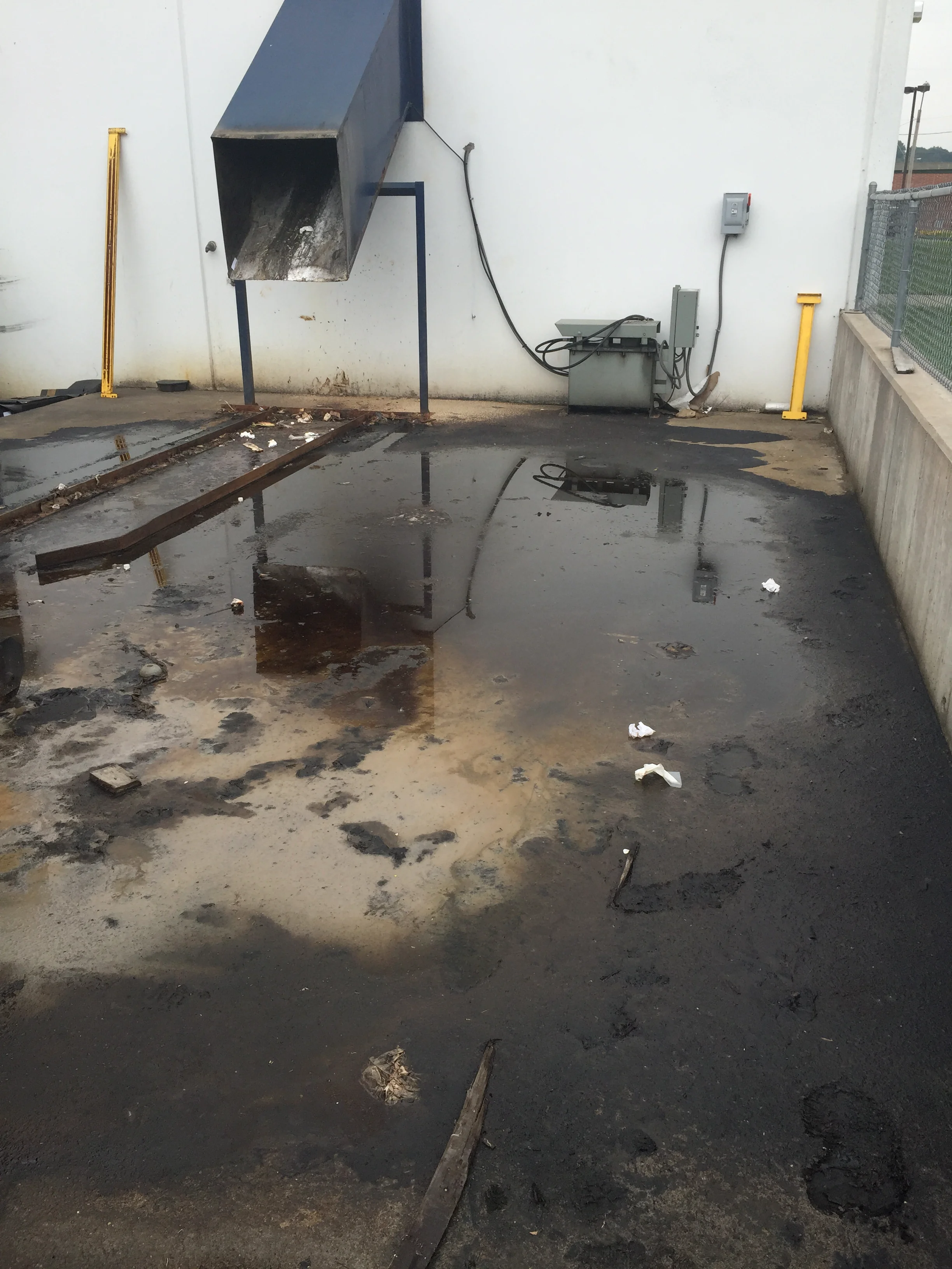 Pressure-washed industrial concrete pad with metal fixtures and drainage system