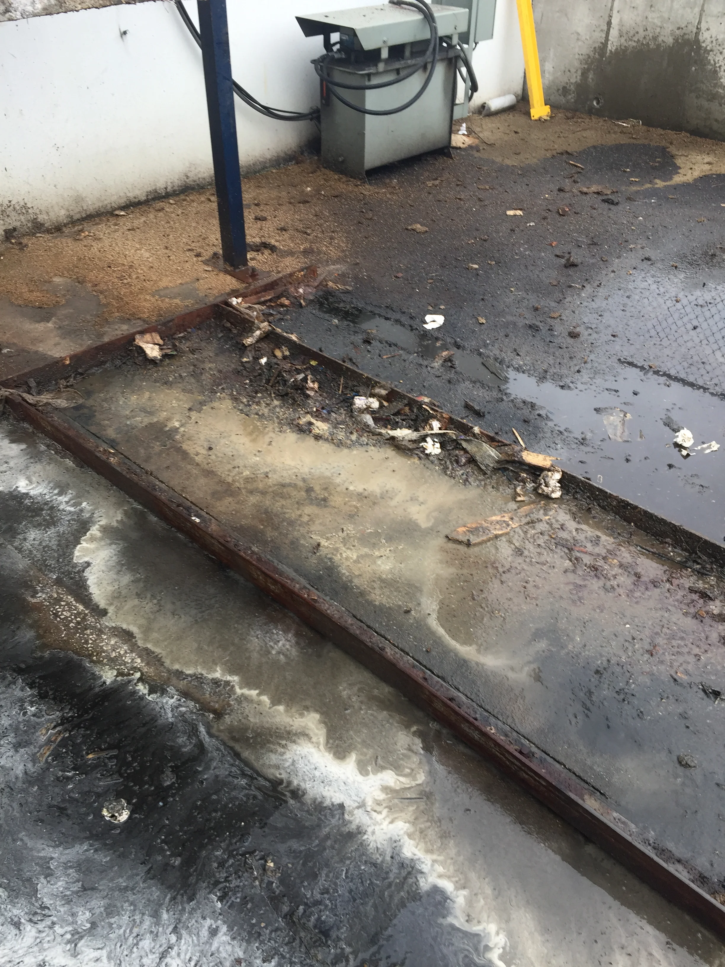 Pressure-washed concrete drainage channel with metal edging, before and after cleaning visible