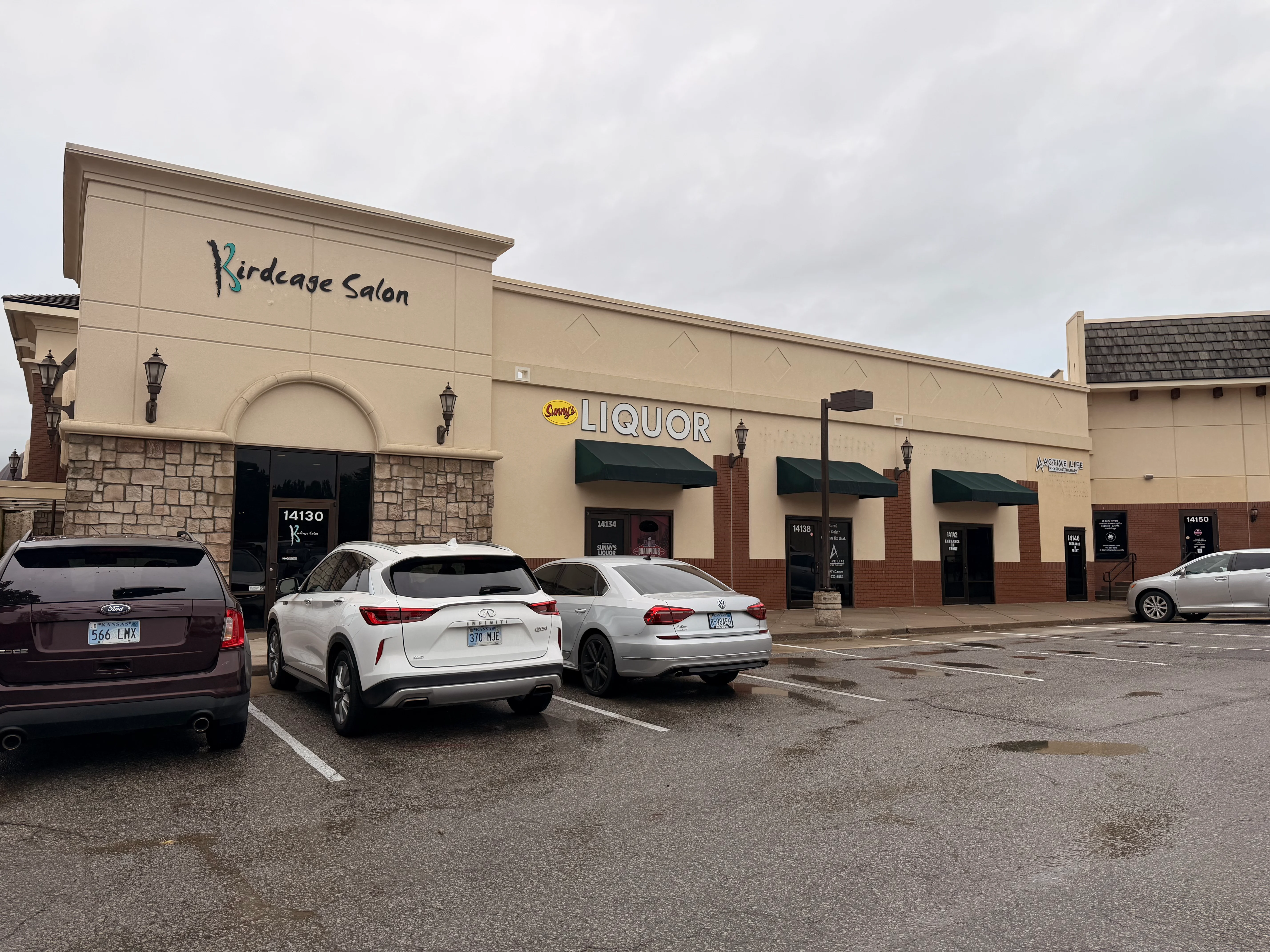 Clean stucco and brick commercial storefront with green awnings and stone veneer base