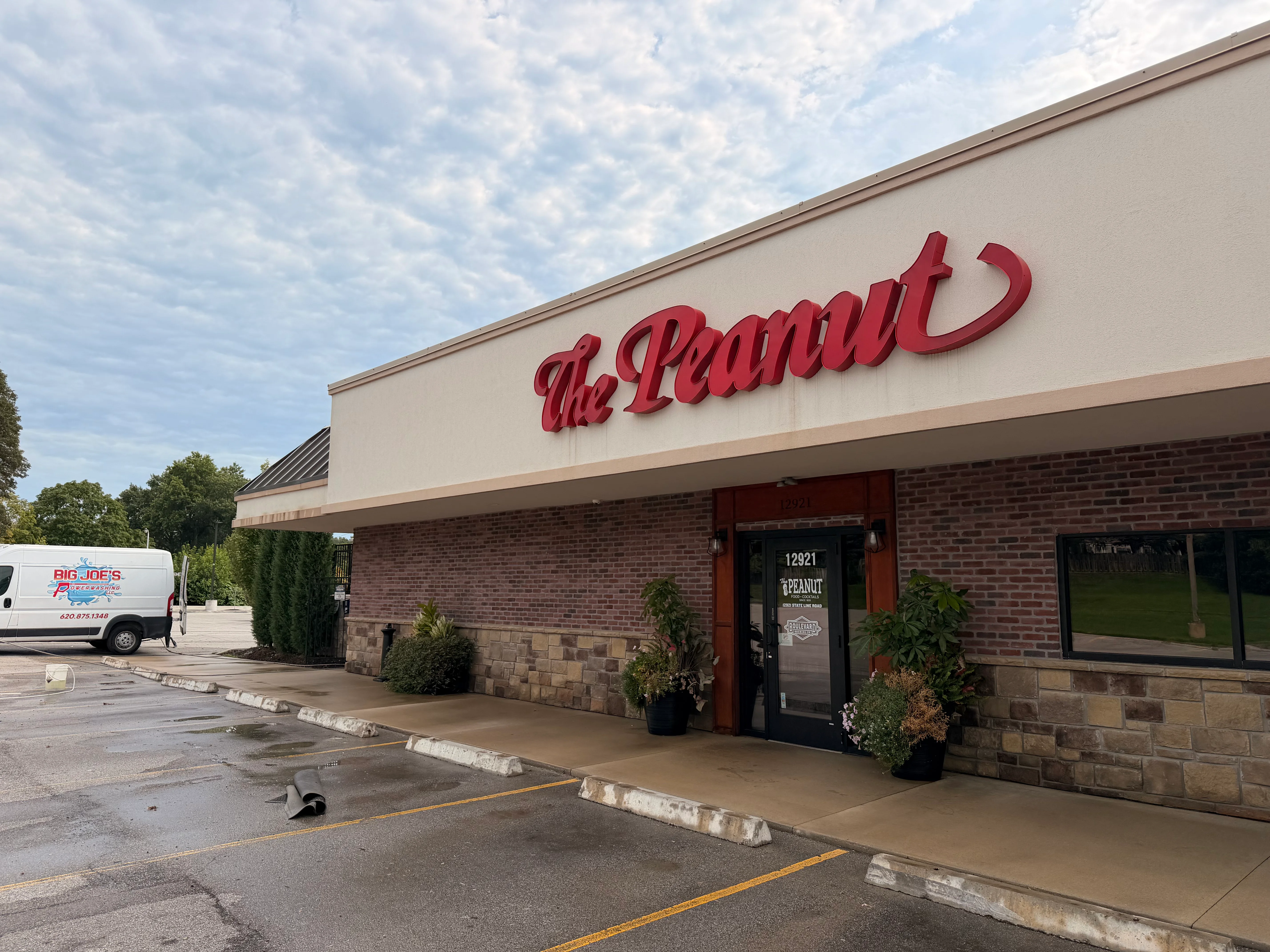 Brick storefront with cleaned concrete walkway and entrance area, red signage visible
