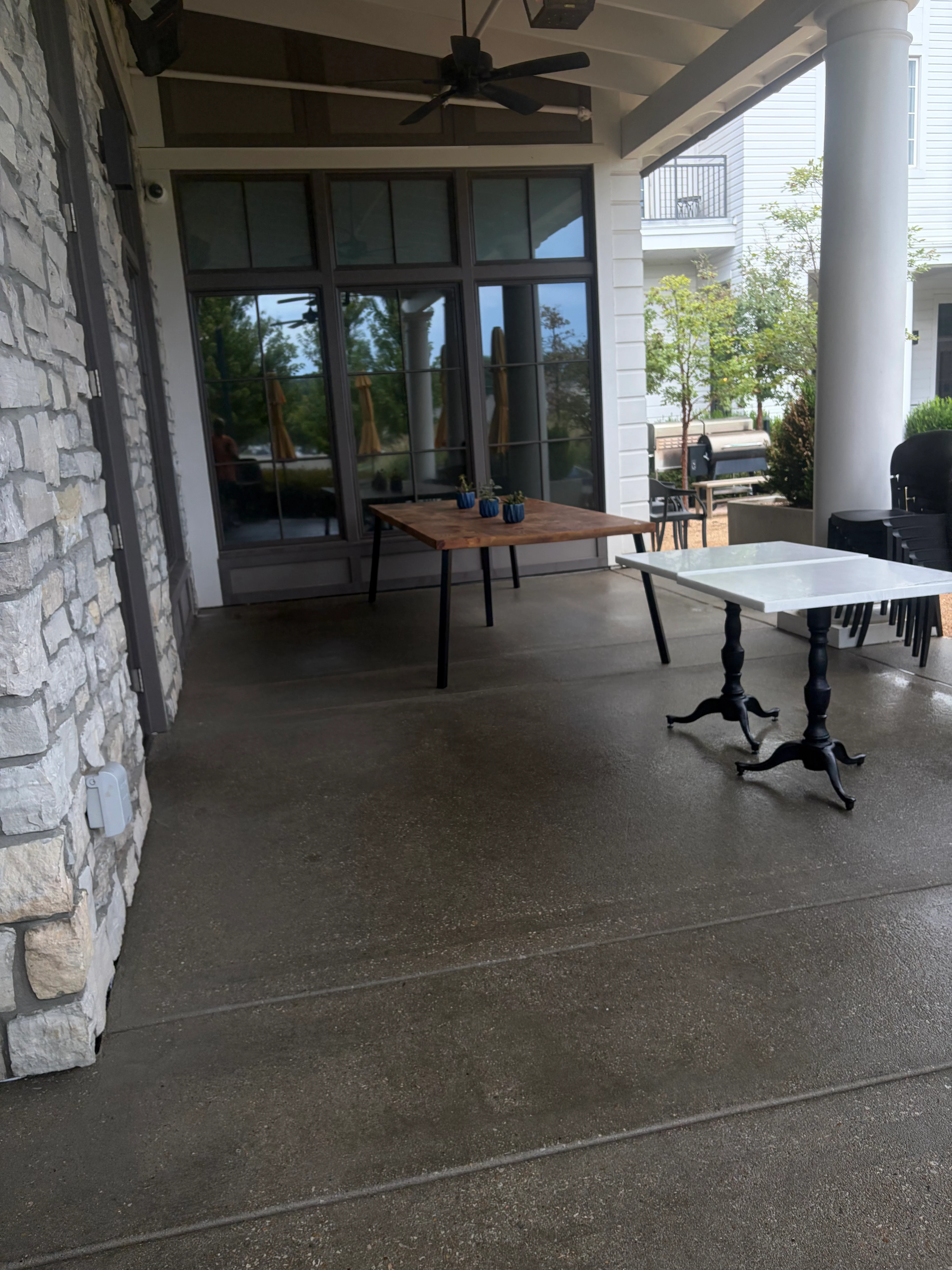 Cleaned concrete patio with white brick columns and black ceiling fan under covered structure