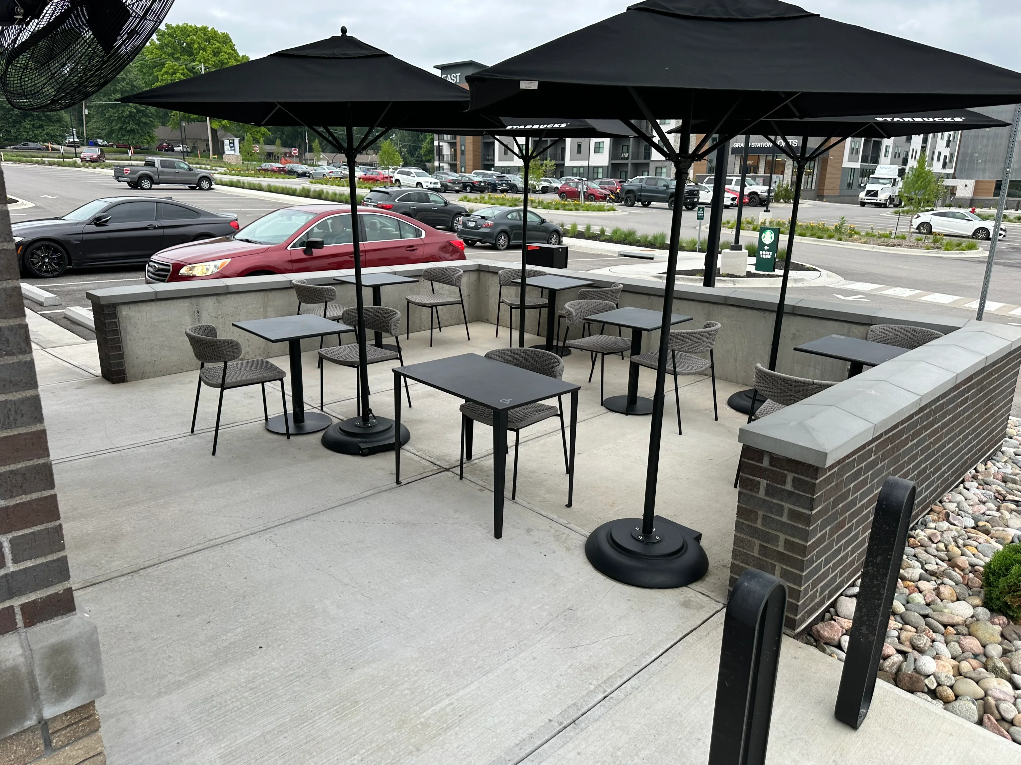 Clean concrete patio with brick planters, stone landscaping, and outdoor dining furniture