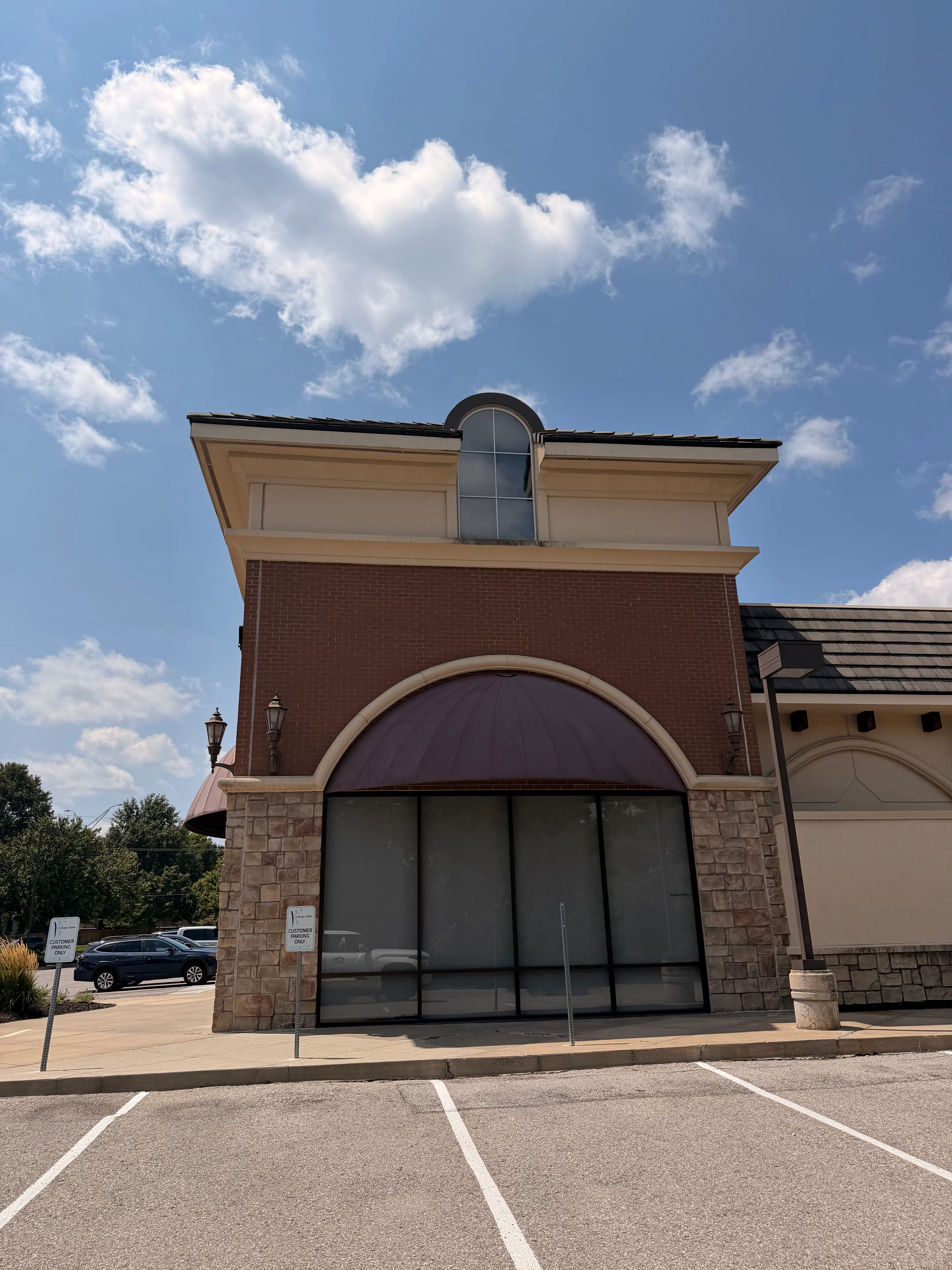 Red brick and stone commercial building facade with cleaned storefront entrance and black-framed glass doors
