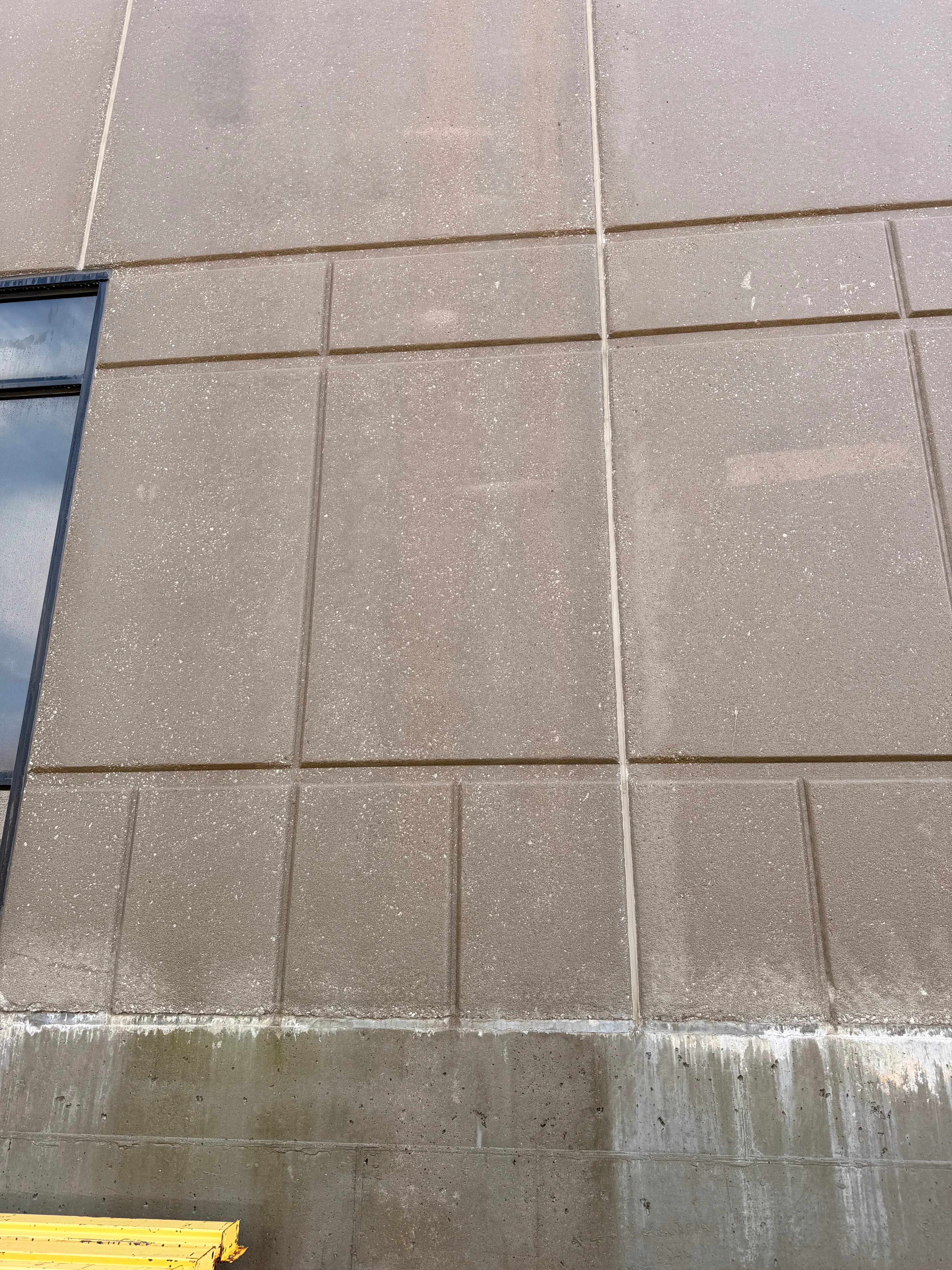 Concrete panel wall cleaned with pressure washing, algae and mold removal on commercial facade