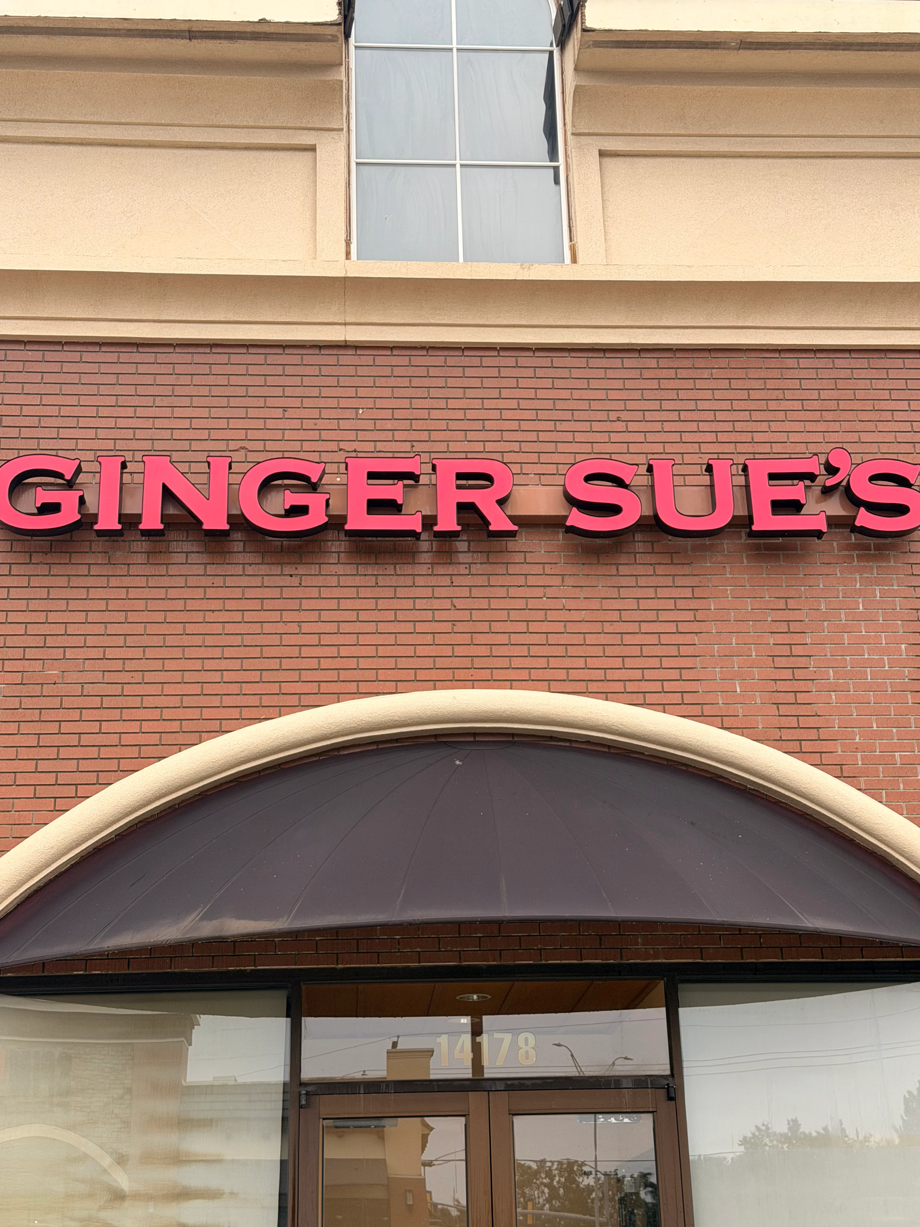 Pink dimensional letters and red brick storefront cleaned on commercial building facade